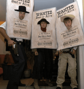 Three people wearing Wanted Dead or Alive poster costumes with cowboy hats