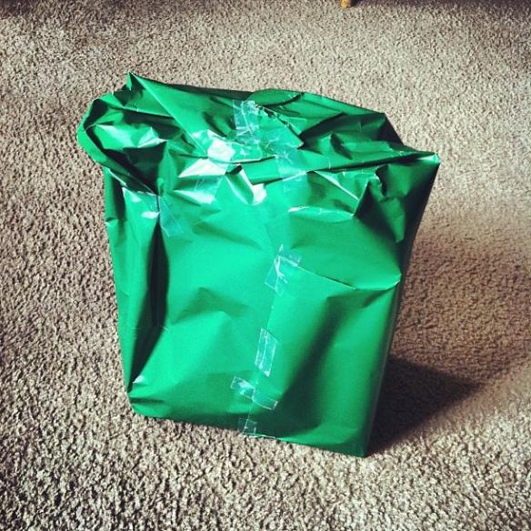 Green present wrapped in crumpled paper and covered in strips of sticky tape